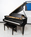Black grand piano with a bench in a room with a white wall and a blue abstract painting.