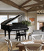 Black Kawai GL-10 grand piano in a modern living room with wooden beams and large windows.